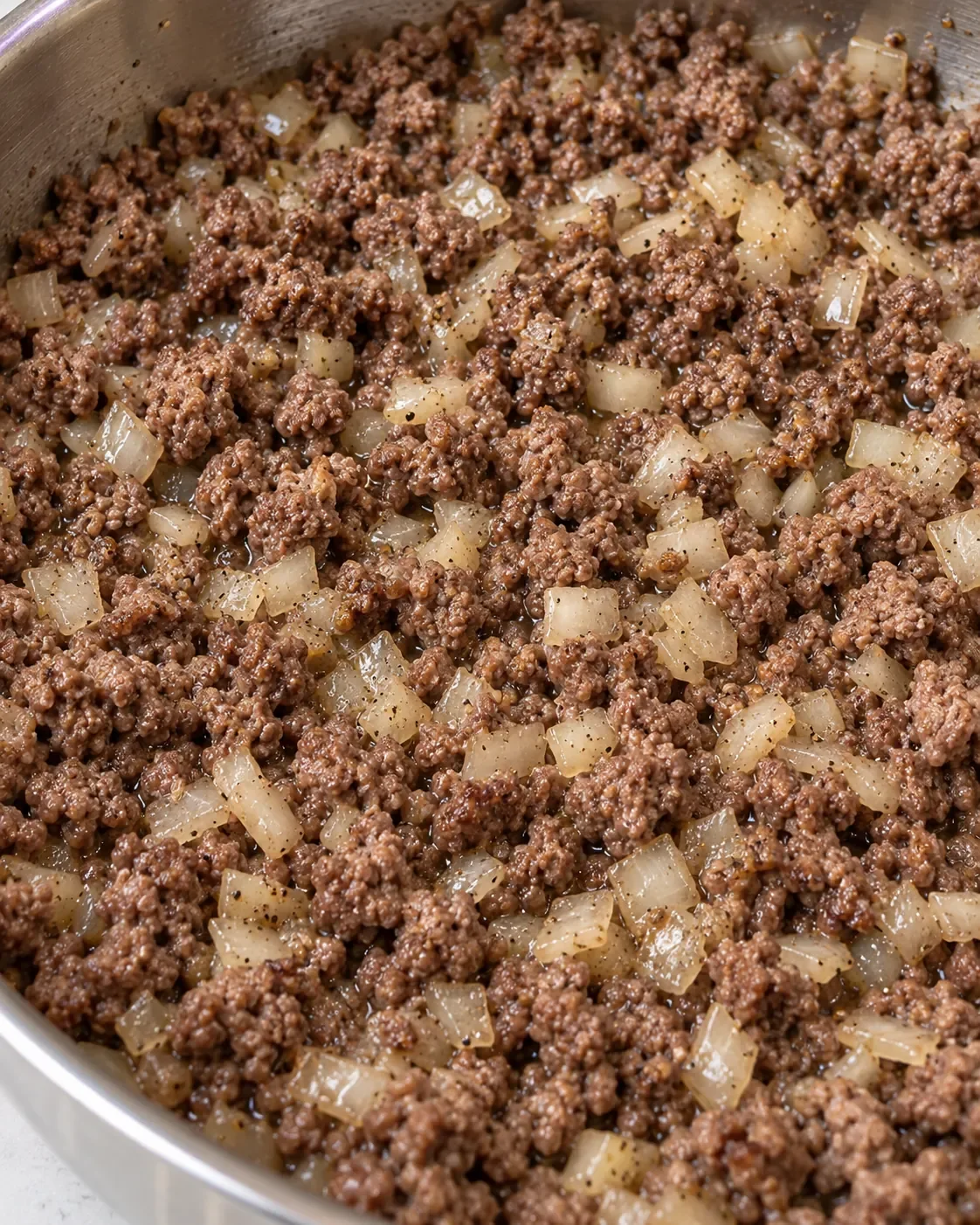Cooked ground beef and softened onion in a stainless-steel skillet before adding the sauce.