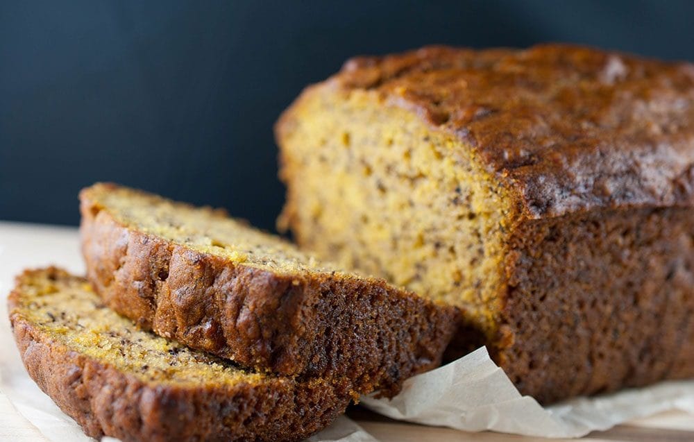 A freshly baked pumpkin banana loaf on a wooden cutting board, sliced to show its moist and fluffy texture.